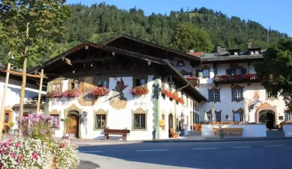 Außenansicht des Posthotels Wallgau mit traditioneller bayerischer Fassade, Blumenkästen und Alpenkulisse im Hintergrund – ideale Hochzeitslocation.