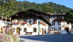 Außenansicht des Posthotels Wallgau mit traditioneller bayerischer Fassade, Blumenkästen und Alpenkulisse im Hintergrund – ideale Hochzeitslocation.