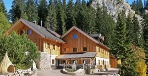 Außenansicht einer modernen, alpenländischen Berghütte unterhalb des Kreuzjoch, eingebettet in felsige Berglandschaft.