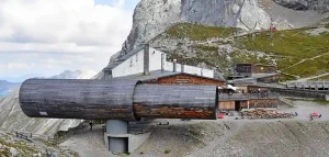 Außenansicht einer modernen, alpenländischen Berghütte in der Alpenwelt Karwendel, eingebettet in felsige Berglandschaft.