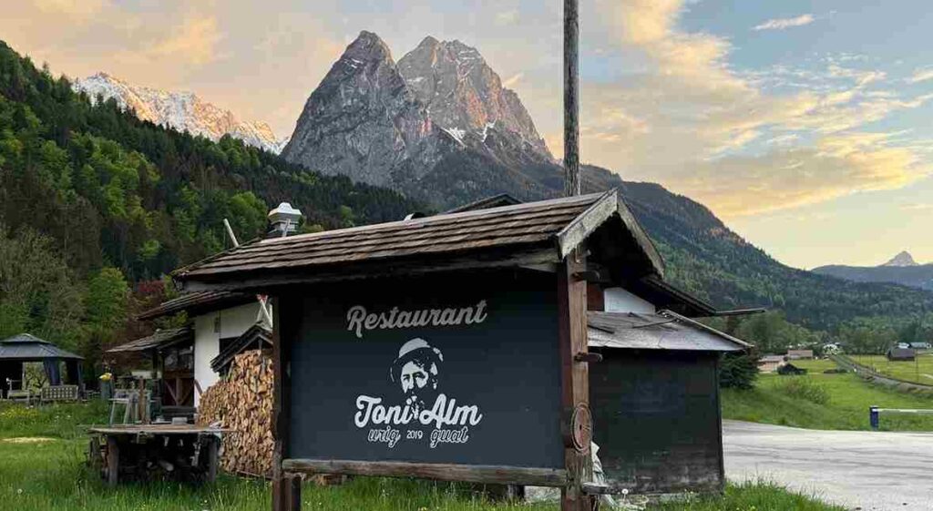 Außenansicht der Toni Alm in Garmisch-Partenkirchen mit Sonnenterrasse und Alpenpanorama.