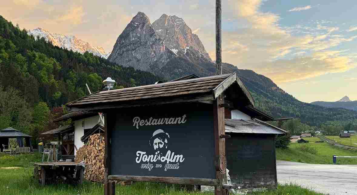 Außenansicht der Toni Alm in Garmisch-Partenkirchen mit Sonnenterrasse und Alpenpanorama.
