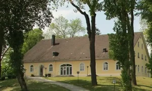 Außenansicht des Café Kellerberg in Ettringen: ein gemütliches Gebäude im modernen Landhausstil, helle Fassade, gepflegte Terrasse und umgebende Grünflächen. Der Eingang wirkt einladend und vermittelt eine warme, ländliche Atmosphäre, ideal für Feiern und Hochzeiten
