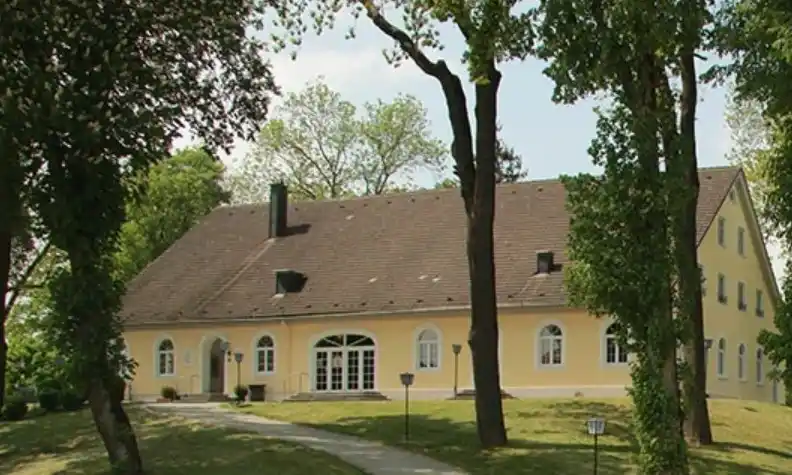 Außenansicht des Café Kellerberg in Ettringen: ein gemütliches Gebäude im modernen Landhausstil, helle Fassade, gepflegte Terrasse und umgebende Grünflächen. Der Eingang wirkt einladend und vermittelt eine warme, ländliche Atmosphäre, ideal für Feiern und Hochzeiten