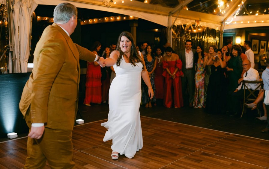 Braut und Bräutigam tanzen ihren Hochzeitstanz auf einer beleuchteten Tanzfläche im Burgrestaurant Gebhardsberg, während festlich gekleidete Gäste im Hintergrund zuschauen und applaudieren.