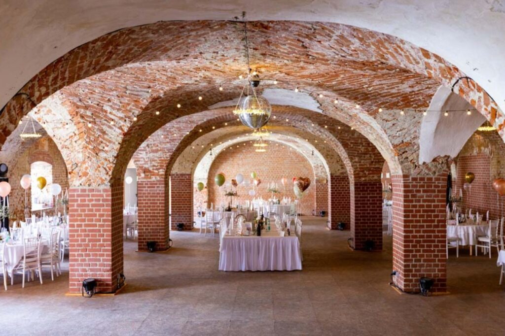 Hochzeit im Prielhof Scheyern mit festlich gedeckten Tischen unter historischen Backsteingewölben und romantischer Beleuchtung